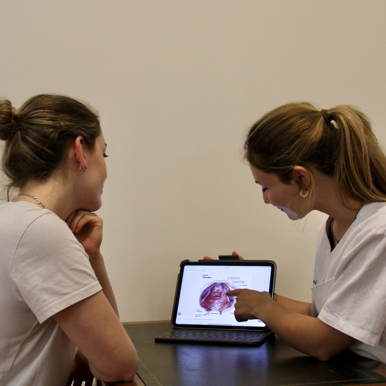 Osteopatia con Chiara Debernardi osteopata MSc Ost Med e membro ROI. Approccio naturale e personalizzato L'osteopata Chiara Debernardi durante una visita osteopatica nel suo studio con ragazza spiega sul tablet il pavimento pelvico