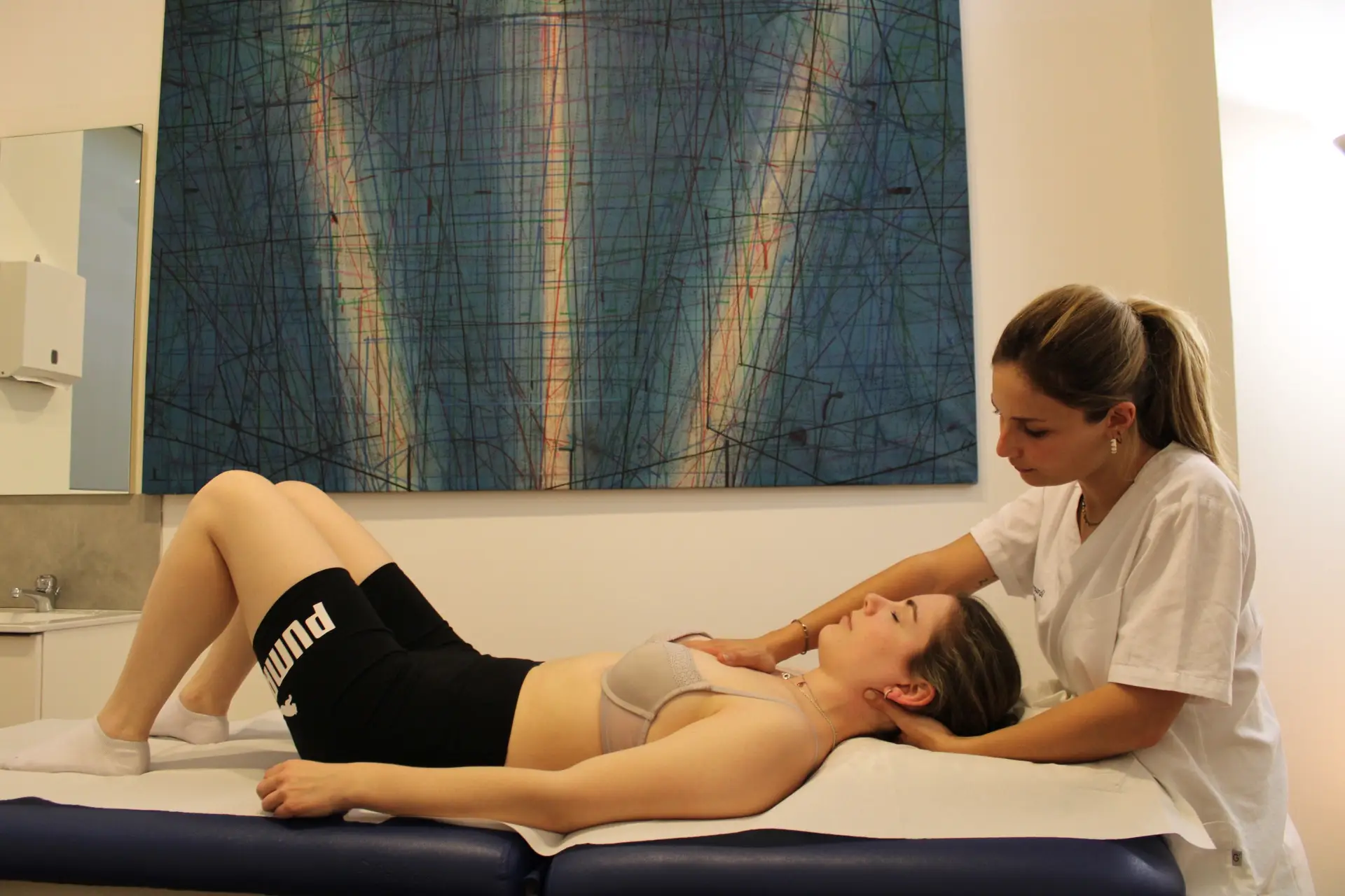 Osteopatia con Chiara Debernardi osteopata MSc Ost Med e membro ROI. Approccio naturale e personalizzato L'osteopata Chiara Debernardi durante una visita osteopatica nel suo studio con ragazza in reggiseno e pantaloncini neri supina sul lettino